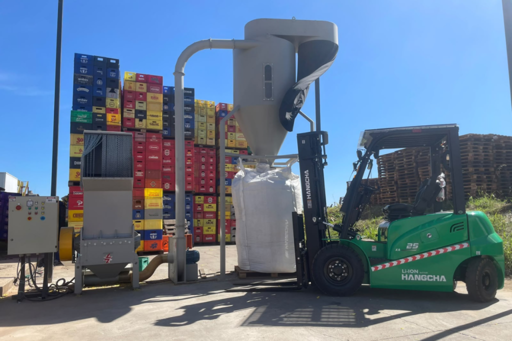 Empilhadeira e engradados plásticos em operação de reciclagem